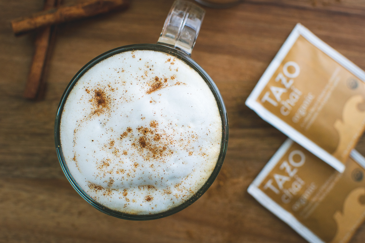 top of pumpkin spice latte with milk froth, pumpkin pie spice, cinnamon sticks and two tazo chai tea bags