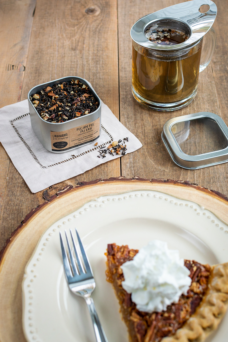 old barrel tea tin of pecan pie pu-erh, tea cup brewing loose leaf tea, and a slice of pecan pie with whipped cream