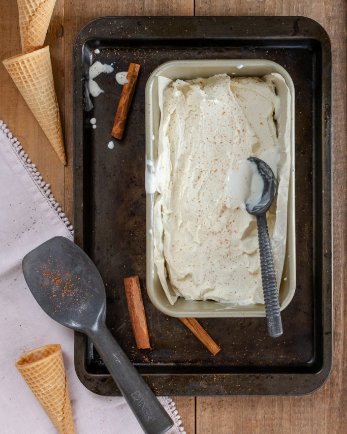 homemade cinnamon tea ice cream in a dish with ice cream cones and an ice cream scoop