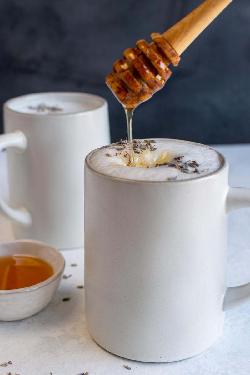 honey dripping onto a lavender honey earl grey latte in a white mug