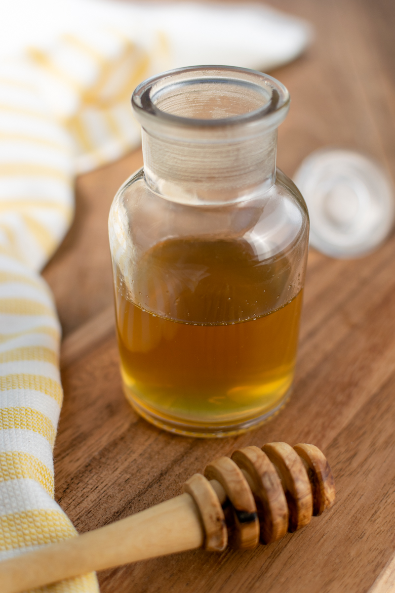 homemade honey simple syrup in a jar with a honey dipper