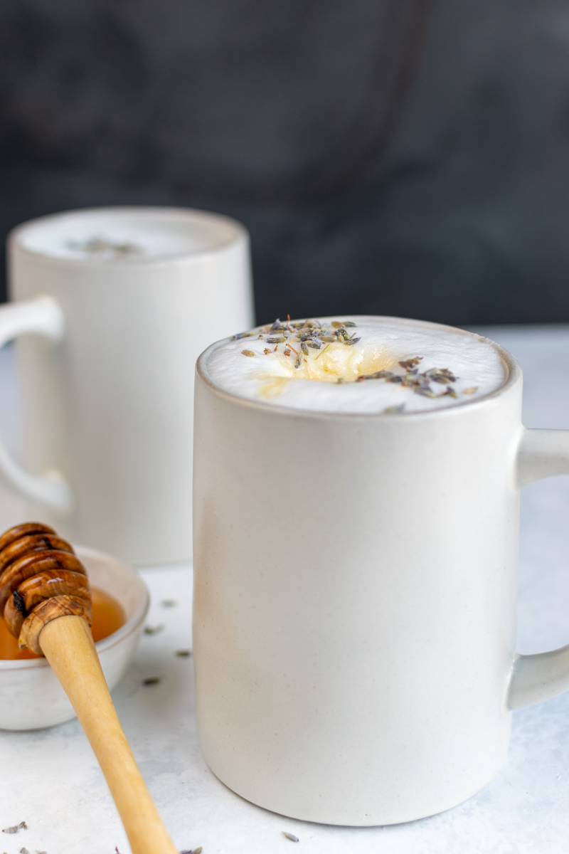 lavender honey latte in mug with honey on top and bowl of honey on the side