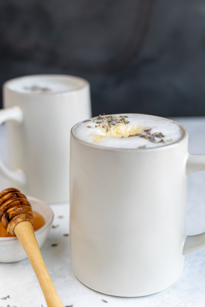 lavender honey latte in mug with honey on top and bowl of honey on the side