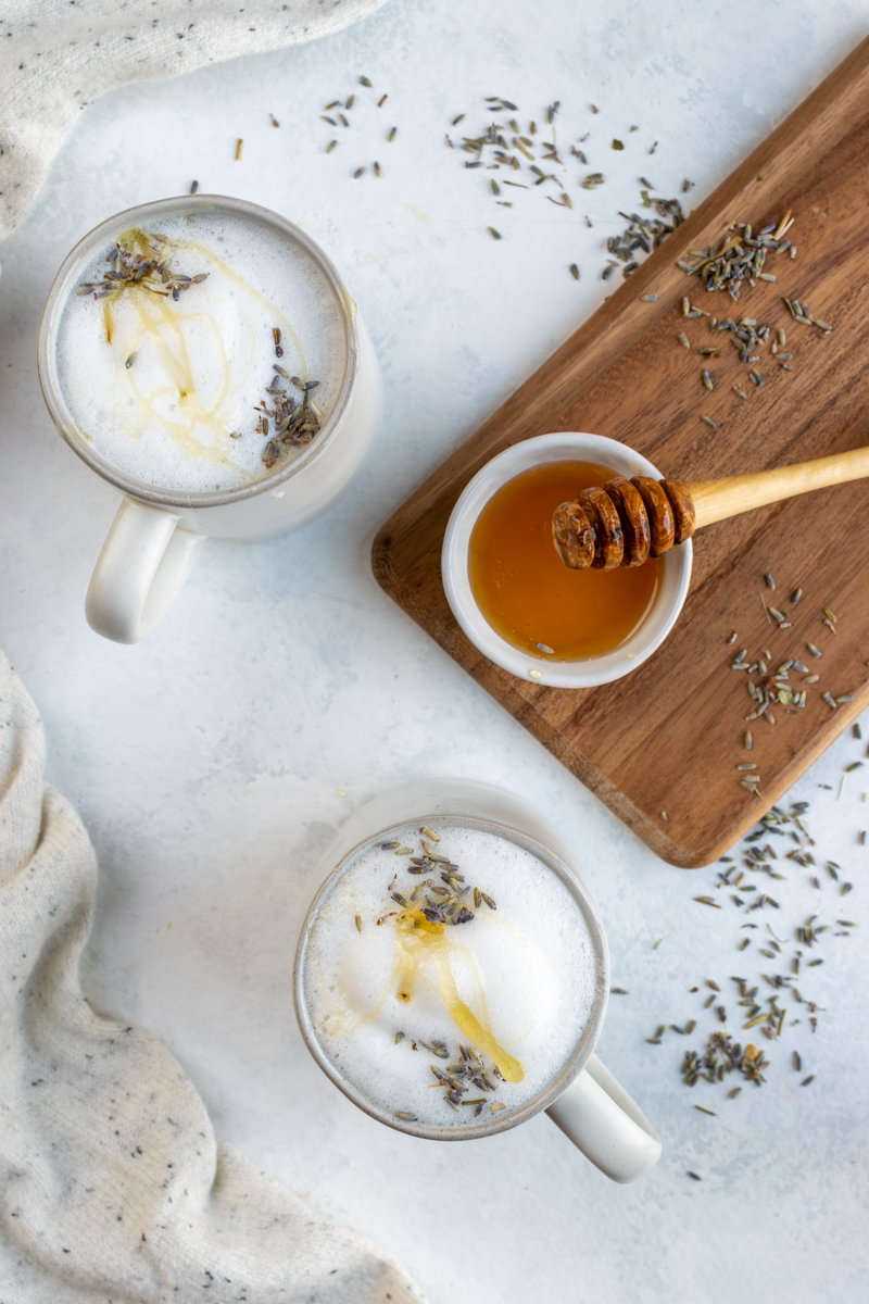 mugs of earl grey lattes with topped with lavender and drizzled honey