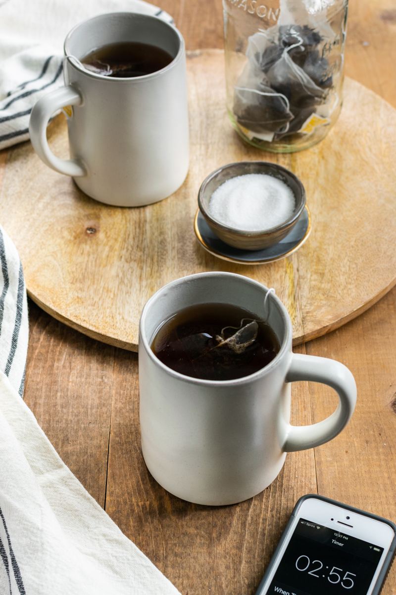 Black tea steeping in mugs with timer