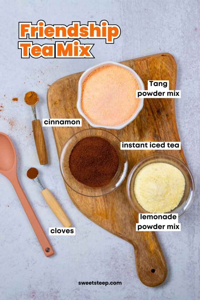 An overhead photo showing the ingredients in bowl and measuring spoons needed to make friendship tea mix. There's Tang orange mix, instant iced tea powder, lemonade mix, cinnamon and clove.