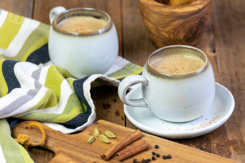 two cups of masala chai with ground cinnamon on top