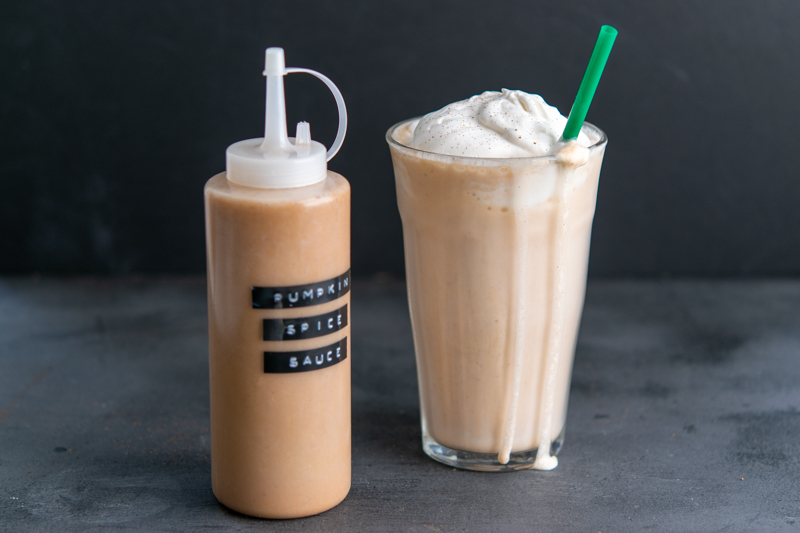 bottle of homemade starbucks pumpkin spice sauce syrup and a frappuccino with whipped cream