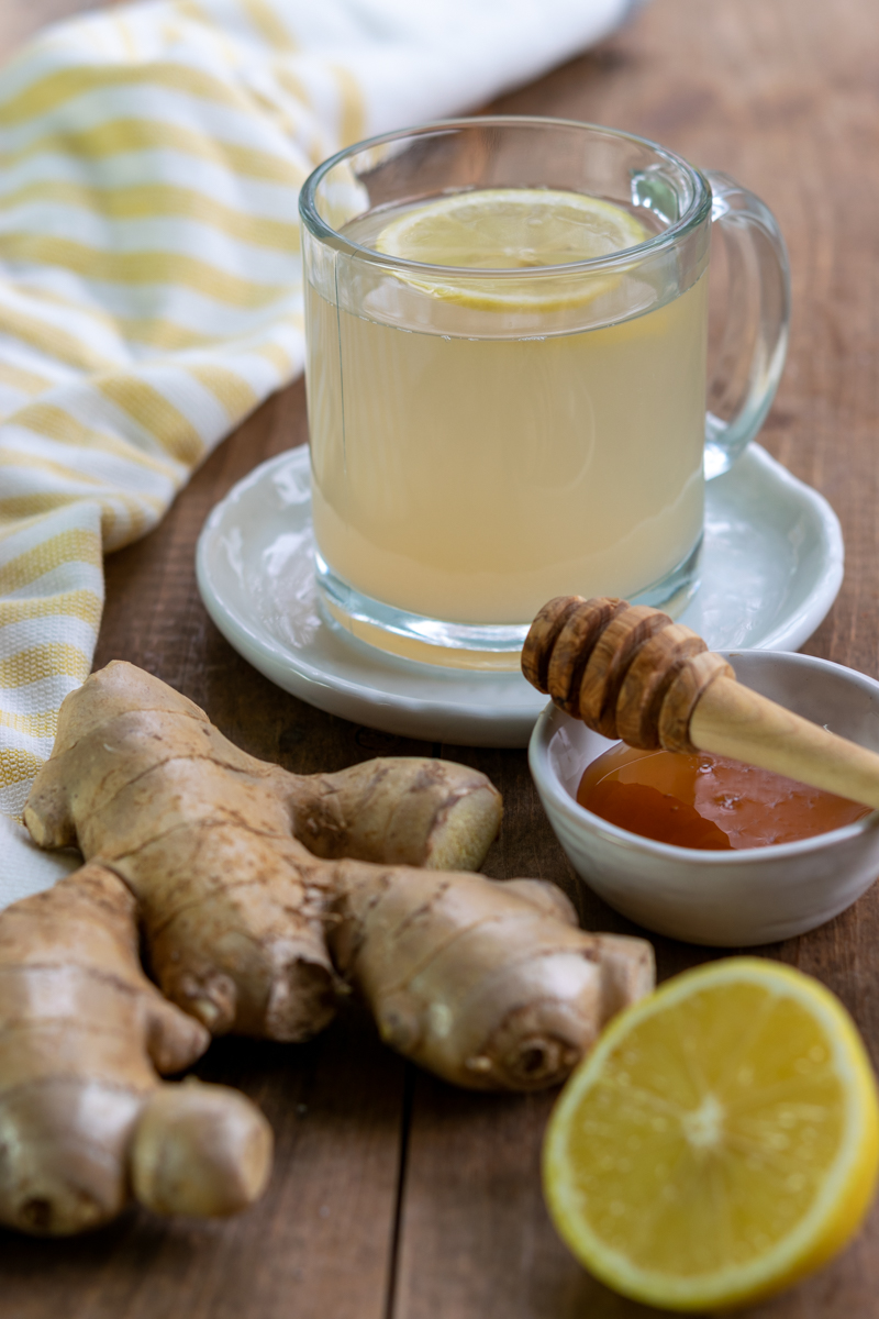 adrak chai recipe ingredients, ginger root, lemon cut in half, bowl of honey