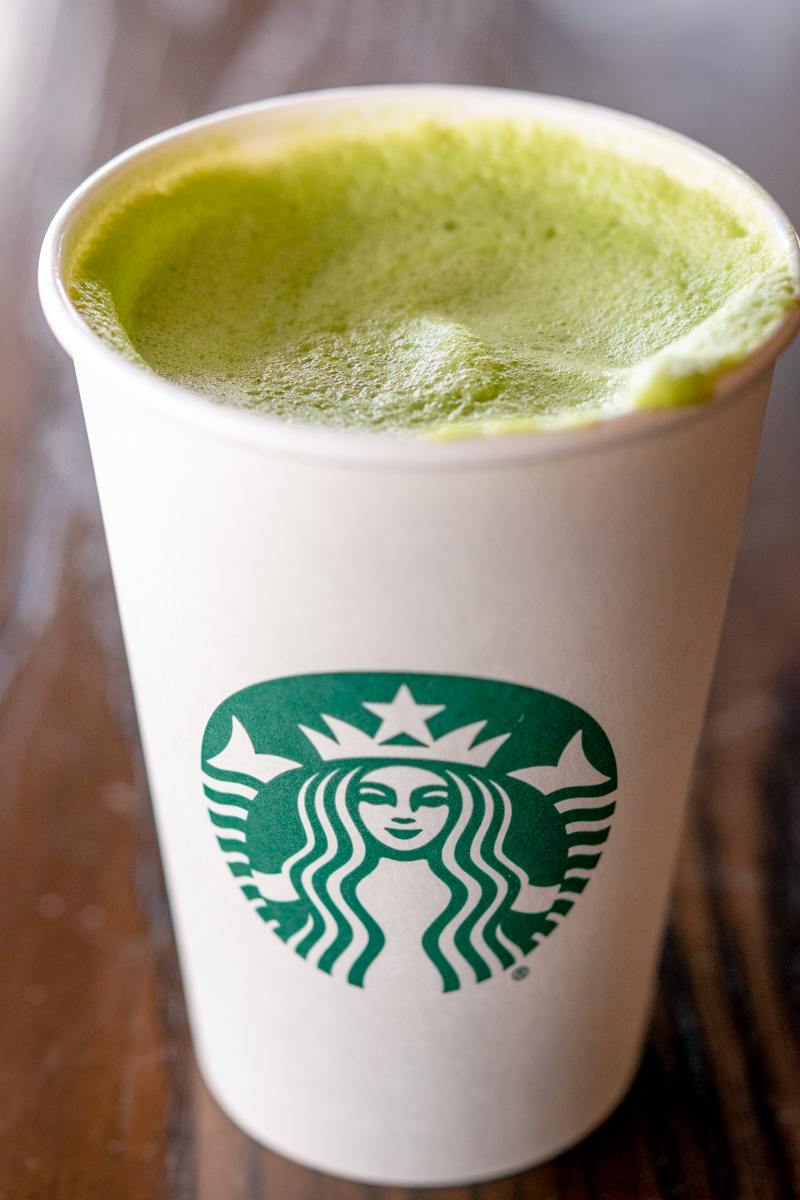 hot starbucks matcha green tea latte in a white cup on a table inside restaurant