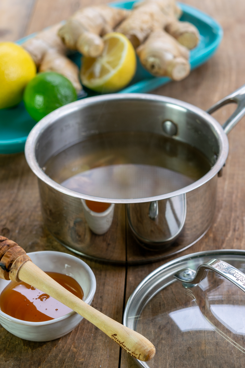 saucepan with boiling water and slices of fresh ginger root