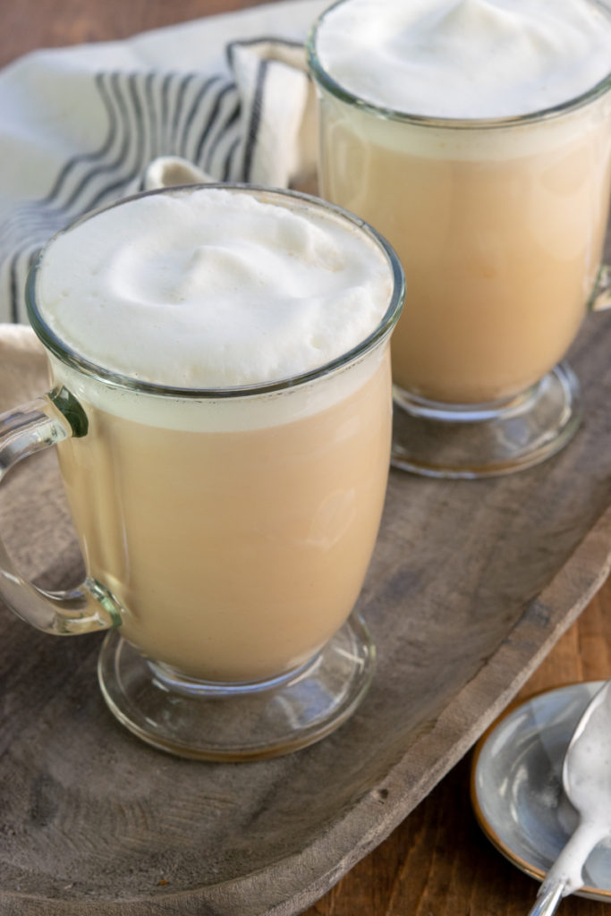 tea lattes in mugs with steamed milk on top