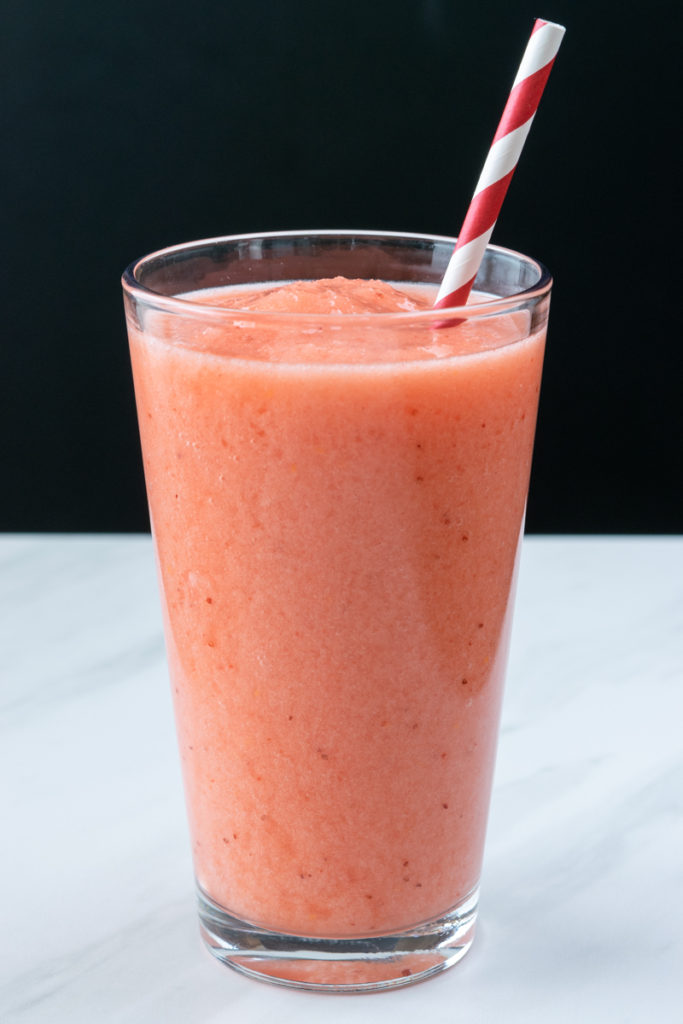 icy strawberry lemonade drink in a glass with a red straw