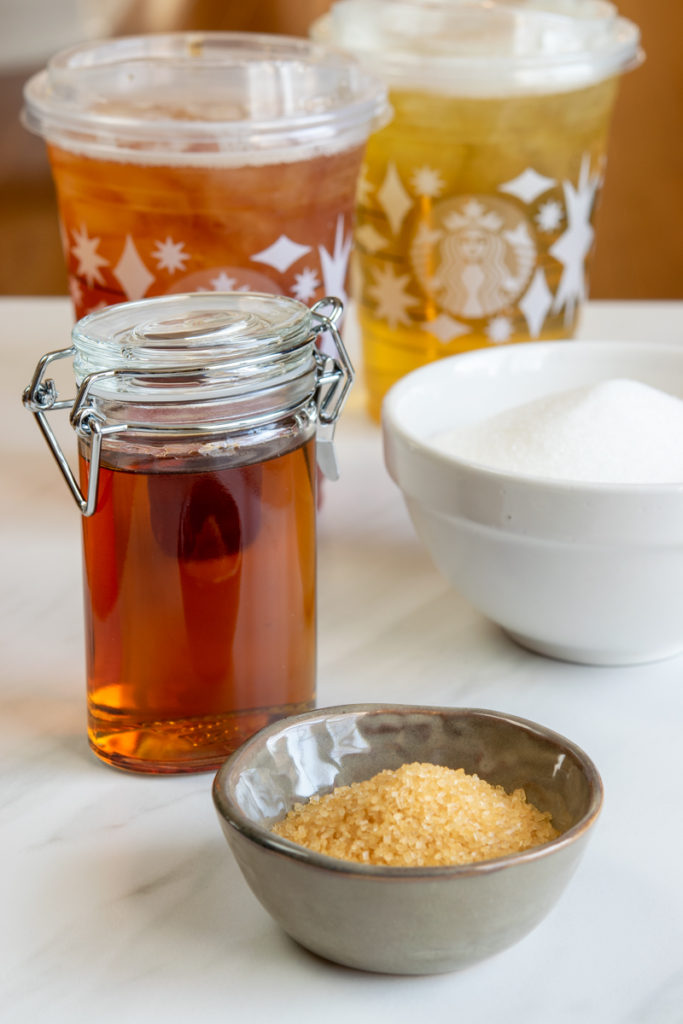 bowl of turbinado cane sugar, bottle of homemade liquid cane sugar and two cups of starbucks iced tea in the background