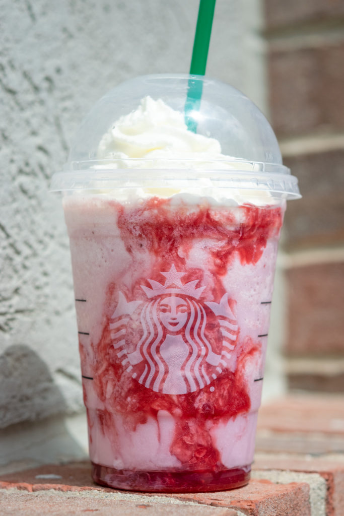 Starbucks Strawberry Creme Frappuccino with whipped cream and a green straw.