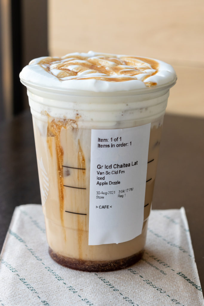 A Starbucks iced chai latte with sticker showing how drink was customized with toppings.