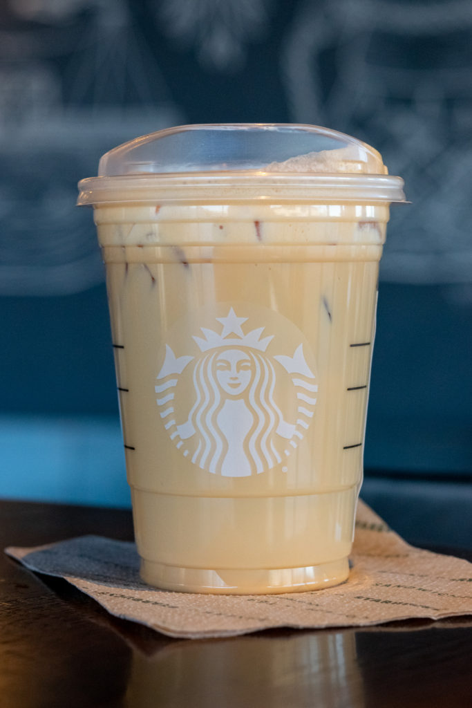 A Starbucks Iced Chai Tea Latte with pumpkin cream cold foam on top of a Starbucks napkin.
