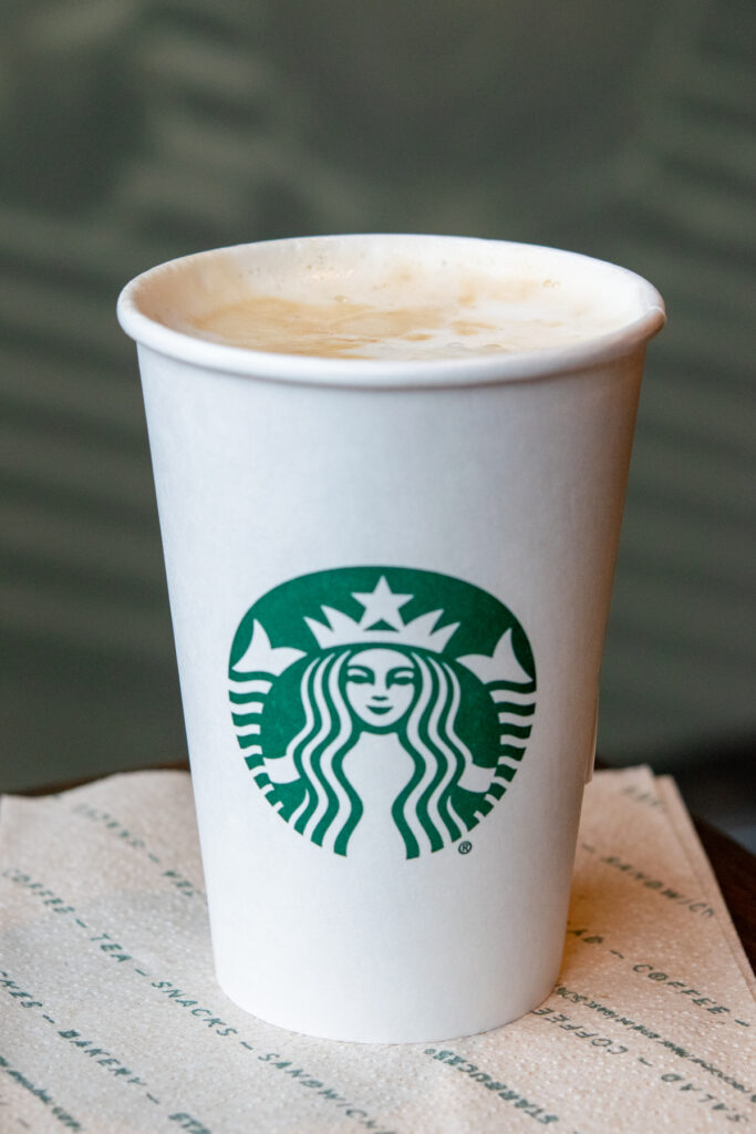 A hot Starbucks dirty chai tea latte with lid off showing creamy chai and espresso.