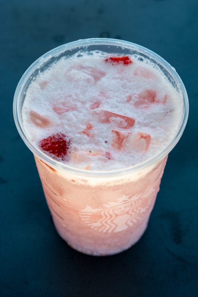 A grande Starbucks Pink Drink with pieces of real strawberry floating on top.