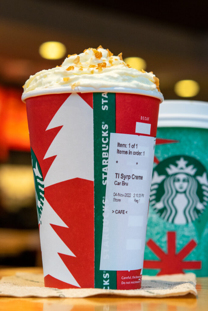 A tall size Starbucks caramel brulee latte in a holiday cup with the order sticker showing.