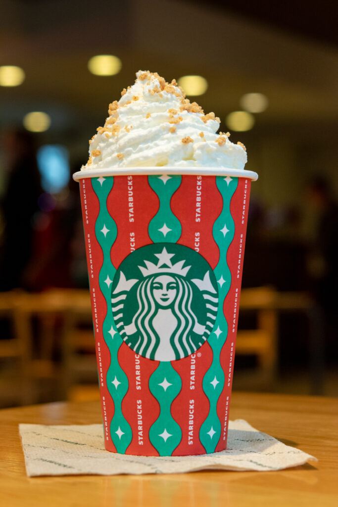 Chestnut Praline Creme in with a big swirl of whipped cream and spiced sugar topping, all in a red holiday cup from Starbucks.