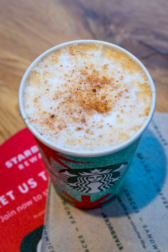 A Starbucks chai tea latte with chestnut praline syrup and spiced praline topping in a holiday cup.