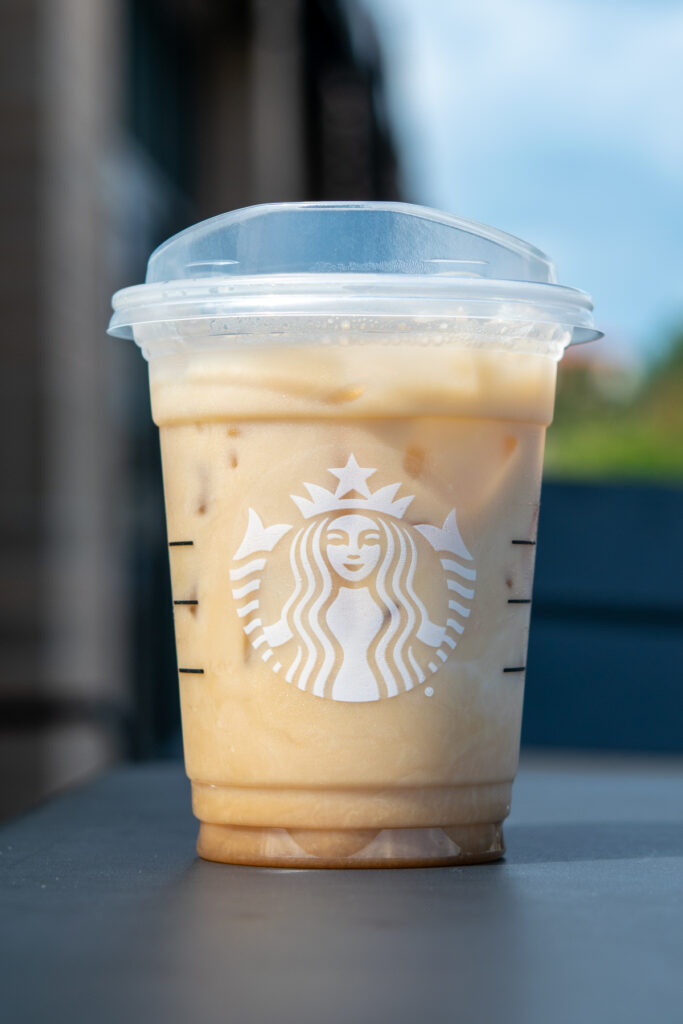 A Starbucks Iced Chai Tea Latte sitting on an outdoor table at Starbucks.