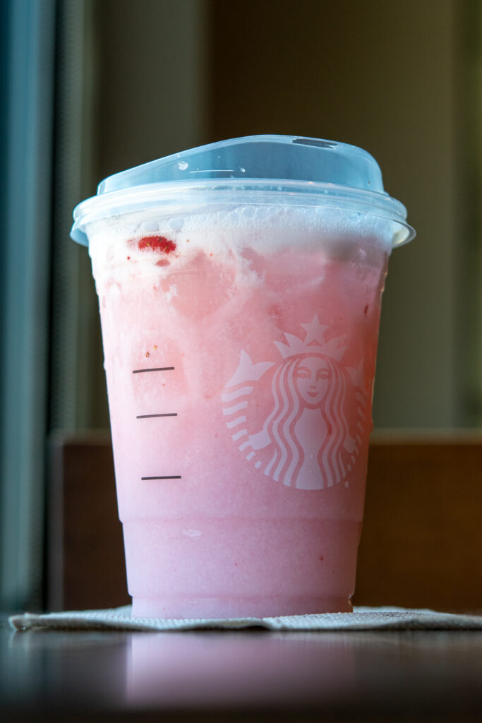 A Starbucks Pink Drink with pieces of strawberry in it.