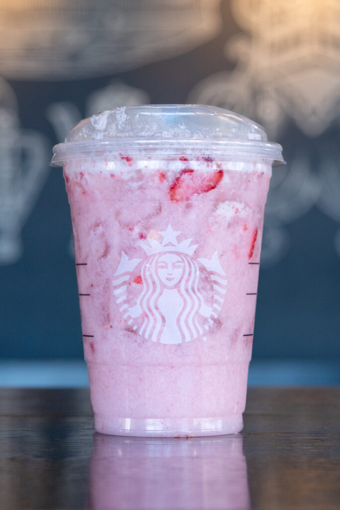 A Starbucks Pink Drink with a few red strawberries floating in it.