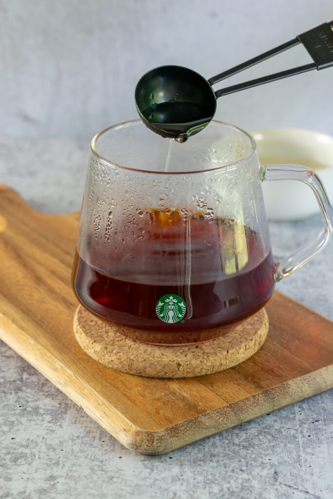 Vanilla syrup being added to cup of brewed earl grey tea.