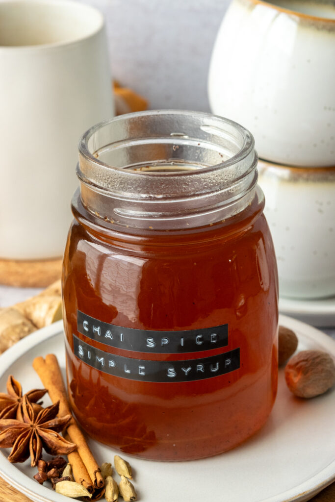 Open jar of homemade chai syrup with an embossed label on it that says, chai spice simple syrup.