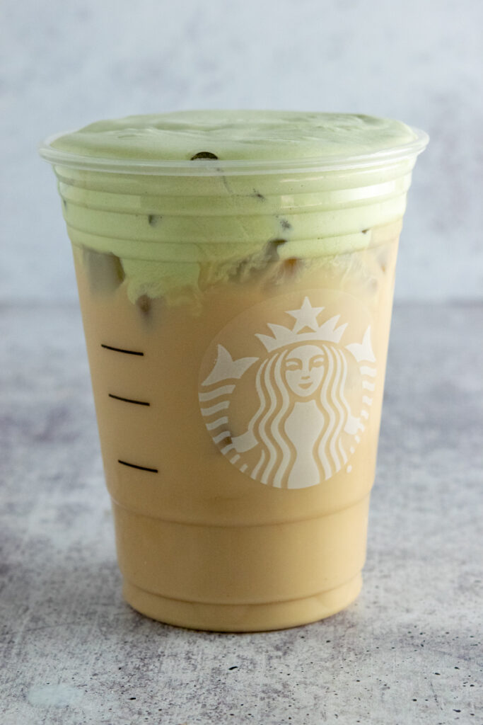 Homemade matcha cold foam iced chai tea latte in a Starbucks cup.