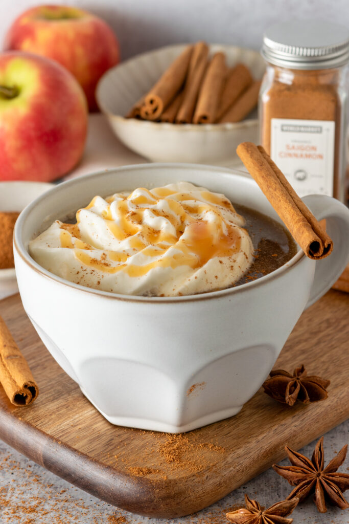 Apple Cider Chai drink topped with whipped cream, caramel sauce and a cinnamon stick.