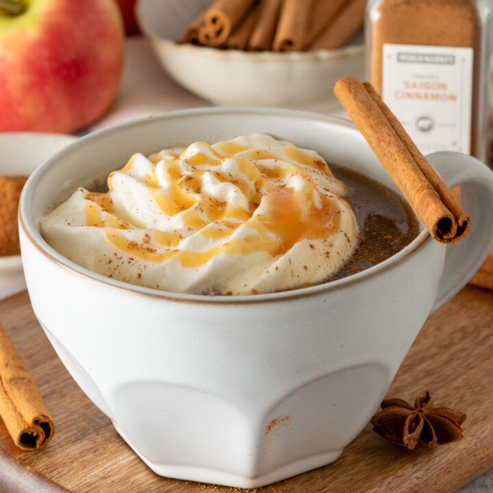 Apple Cider Chai drink topped with whipped cream, caramel sauce and a cinnamon stick.