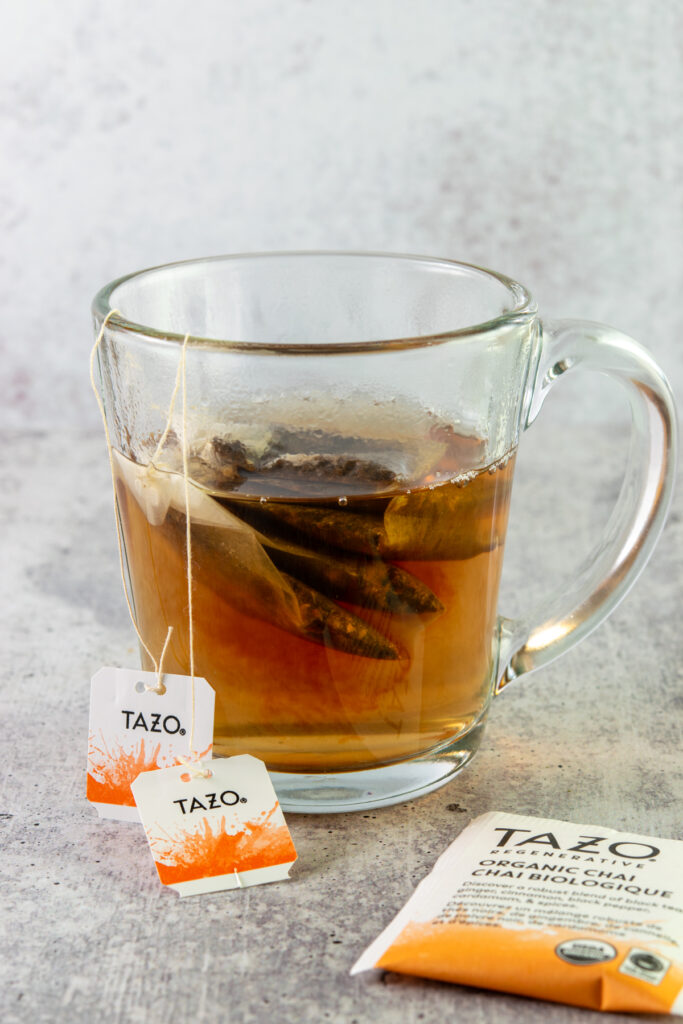 Brewing two chai tea bags in a mug half full of boiling water.