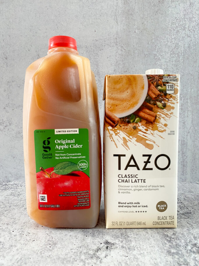 A half gallon jug of apple cider and a box of Tazo classic chai latte black tea concentrate.