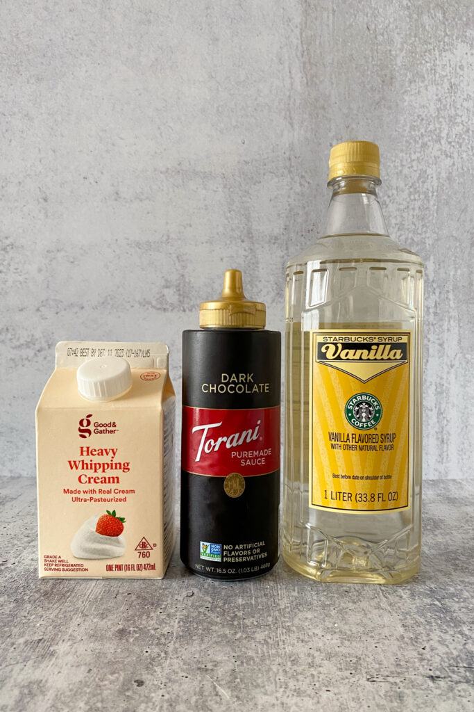Carton of heavy whipping cream, bottle of Torani dark chocolate sauce, and bottle of Starbucks vanilla syrup.