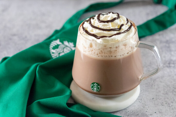 Copycat Starbucks hot chocolate in a Starbucks mug next to a green Starbucks apron.