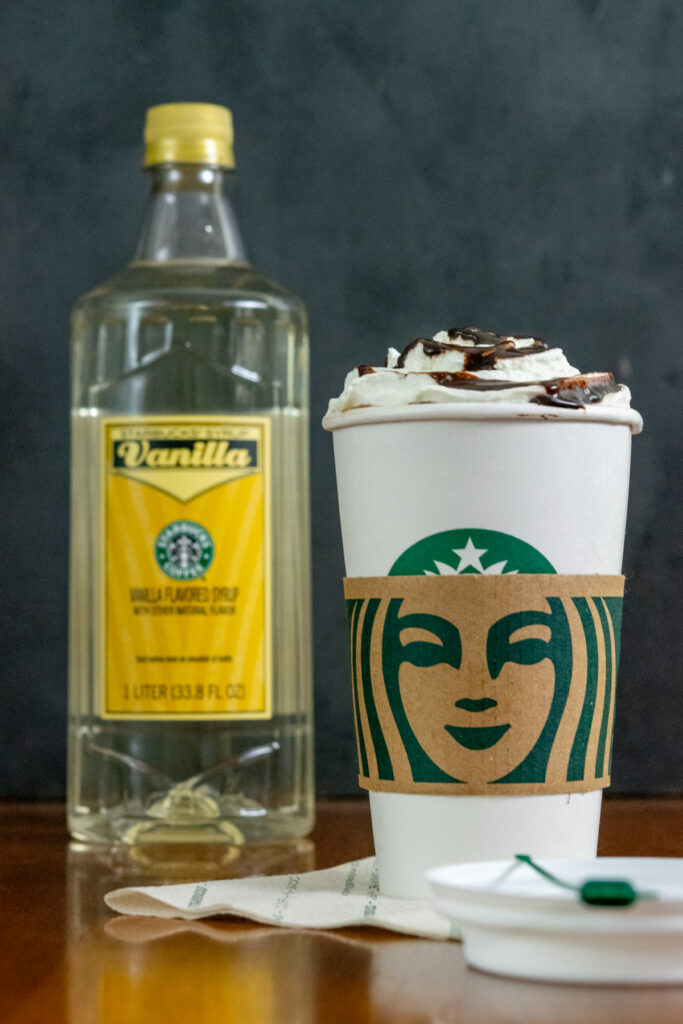 Bottle of Starbucks vanilla syrup and a Starbucks hot chocolate made from the original recipe that had vanilla syrup in it.