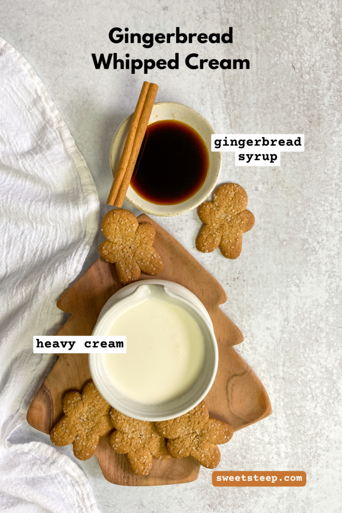 Overhead picture of gingerbread syrup and heavy cream in small bowls with cinnamon sticks and gingerbread cookies scattered around.