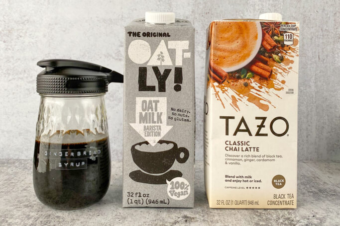 Bottle of homemade gingerbread syrup, Oatly Barista Edition oat milk, and a carton of Tazo chai latte.