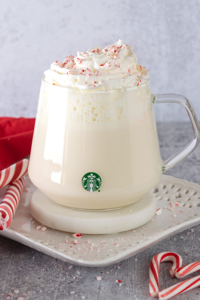 Peppermint white hot chocolate in a Starbucks cup with crushed peppermint candies sprinkled on the whipped cream topping.