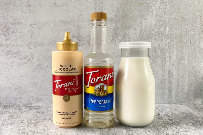 Bottles of Torani white chocolate sauce, Torani peppermint syrup and milk.