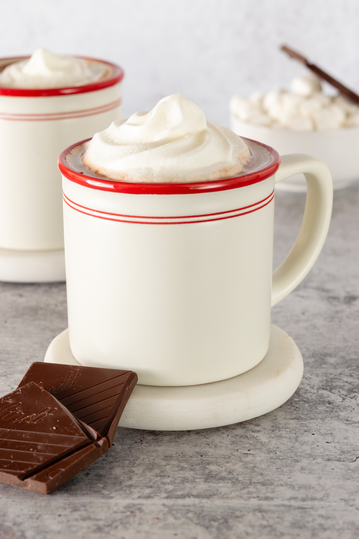 Two cups of creamy homemade hot chocolate and pieces of dark chocolate.