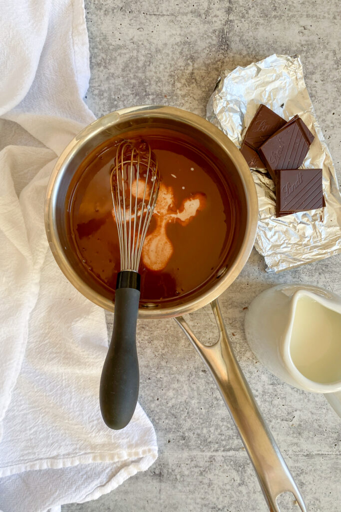 Whisking small amount of milk into melted cream and chocolate mixture.