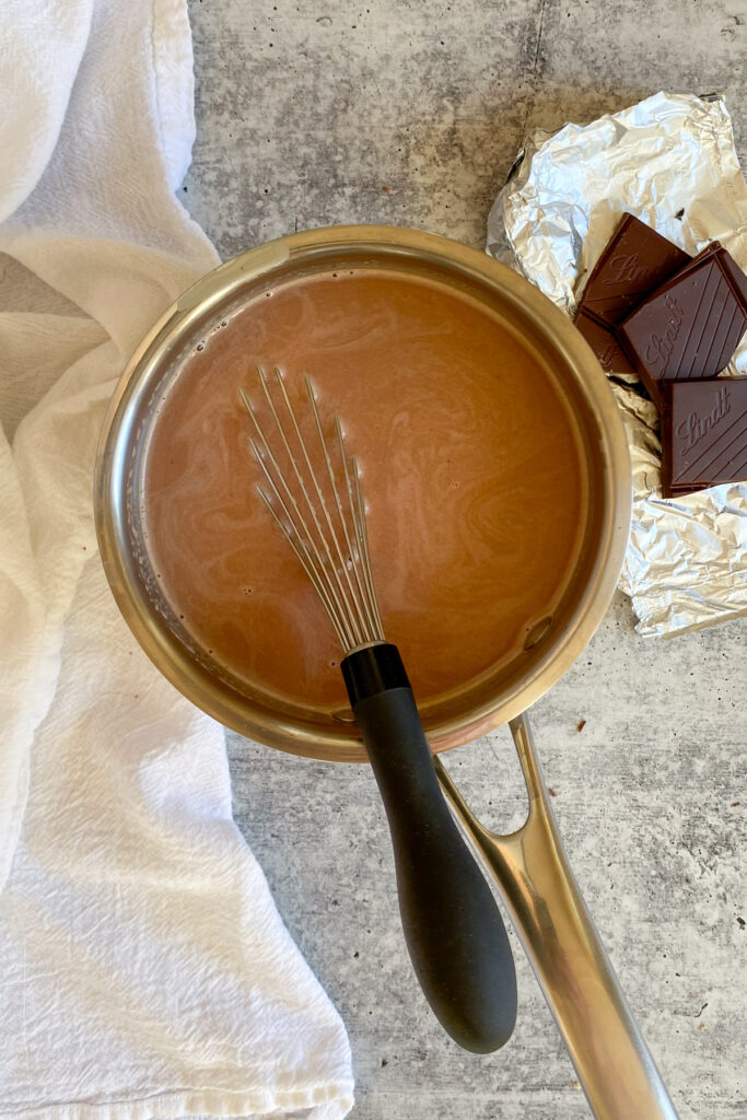Whisking the milk into the chocolate to make hot chocolate.