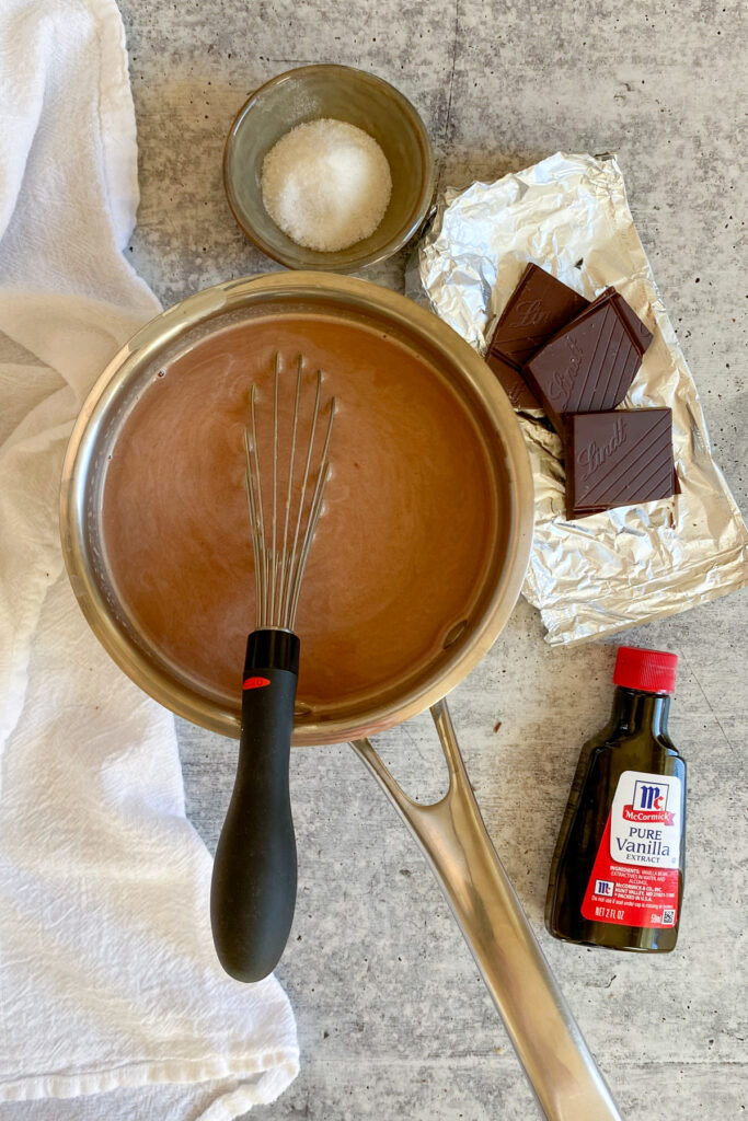 Saucepan removed from heat next to a bottle of vanilla extract and small bowl of sea salt.