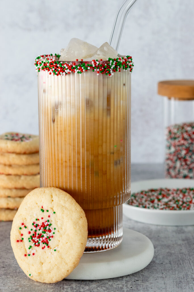 An iced sugar cookie latte that was flavored with the copycat Starbucks sugar cookie syrup, The drink rim is garnished with sugar cookie sprinkles.