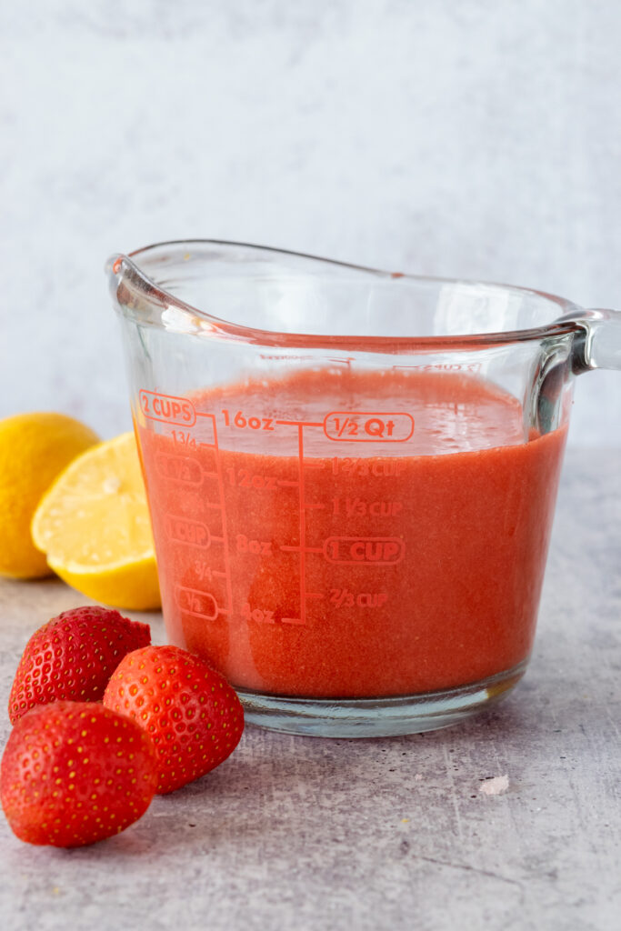 Homemade strawberry puree in a glass Pyrex measuring cup showing that the recipe makes 1 3/4 or 14 fluid ounces of puree.