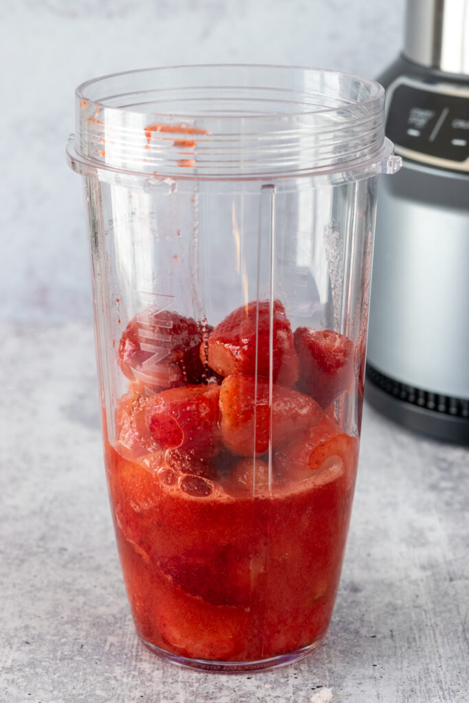 Strawberries, sugar, and juice extracted from berries  in a blender.